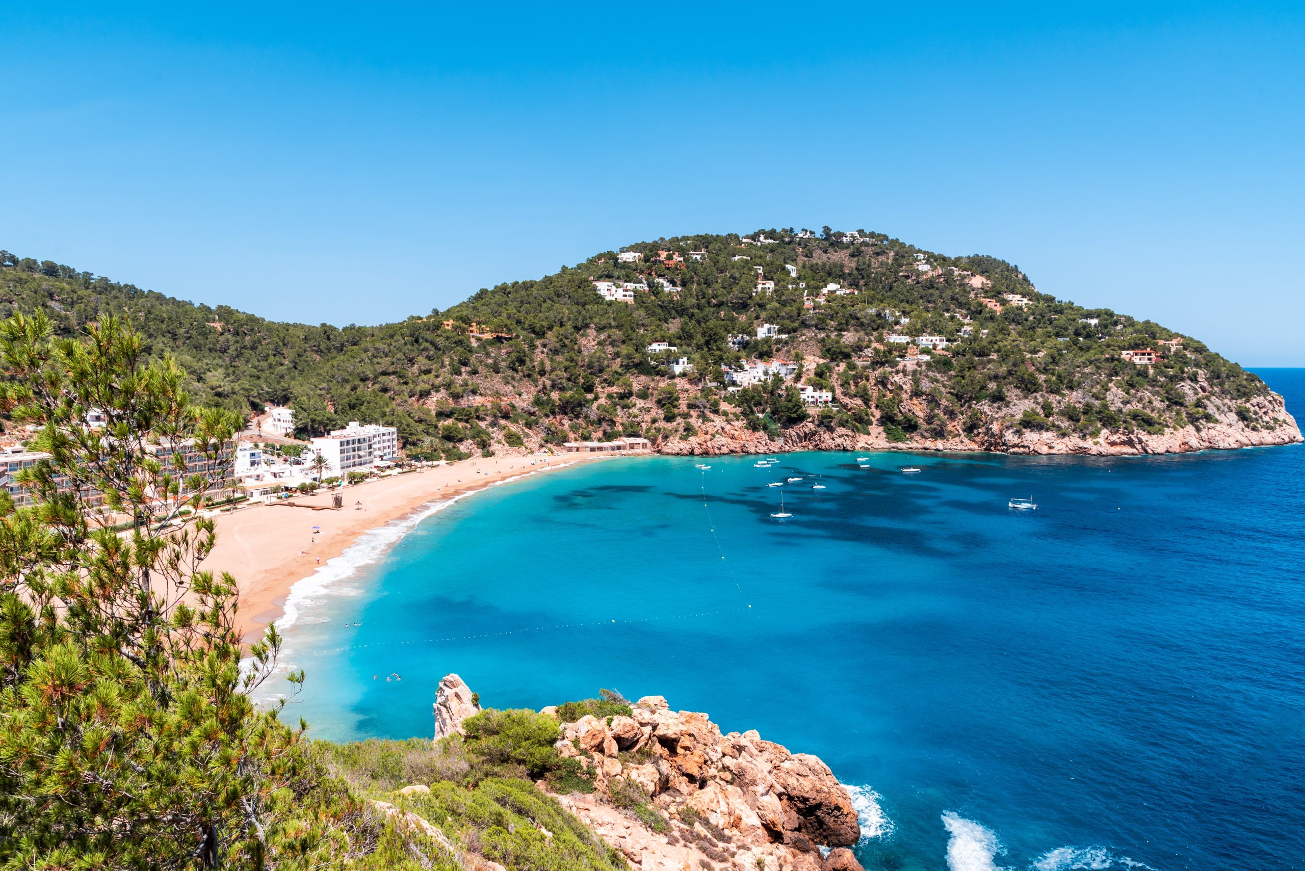 beach with crystal blue water and rocky hills in Ibiza, Spain