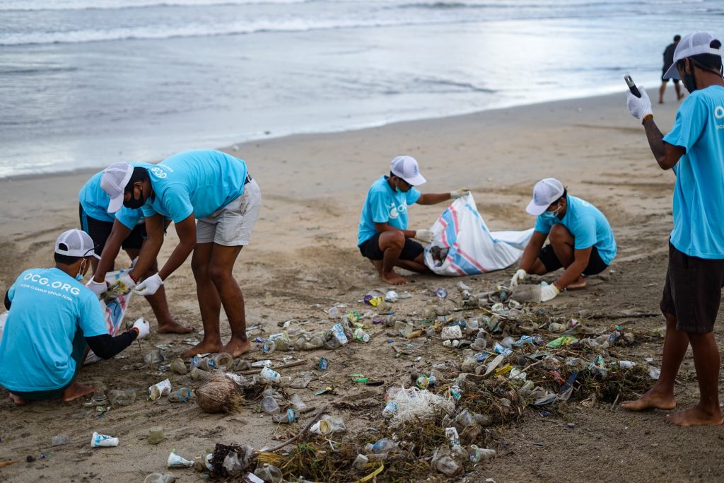 team of volunteers picking up trash at an organized beach cleanup